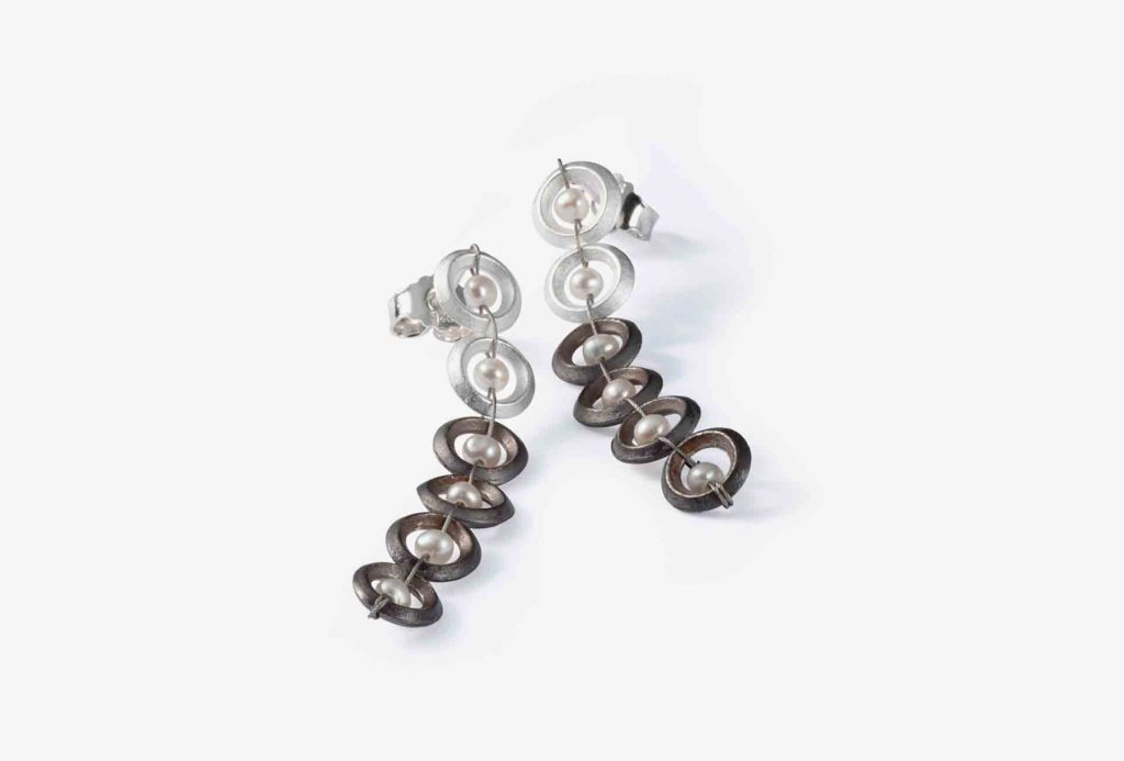 <em>Pearl row</em> earrings. Silver 925, silver black rhodinum-plated, white freshwater pearls, stainless steel rope.