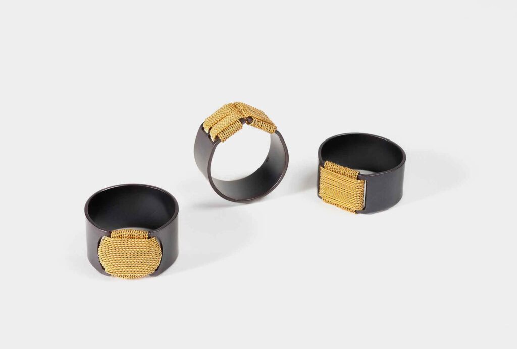 Rings <em>Nähen Dach-Terrasse mit Sonne</em> [sewing roof terrace with sun], blackened stainless steel, gold.