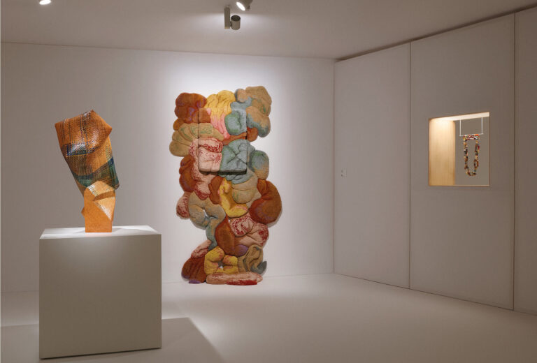 Exhibition space at the Thyssen-Bornemisza National Museum. <em>Radiance Amidst Uncertainty</em>, 2020, by Akari Aso, Japan (left). <em>Sobejos XII</em> by Jessica Costa, Brazil. Wool, resin, wood, 130 x 220 x 50 cm, 2024. This tactile work bridges the gap between sculpture and textiles (center). <em>Hollow Stripe Chain</em> by Caroline Broadhead (right).