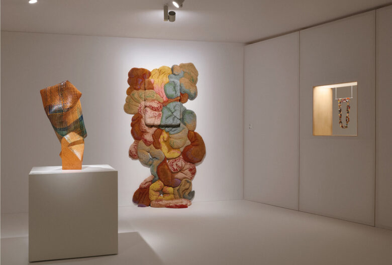 Exhibition space at the Thyssen-Bornemisza National Museum. <em>Radiance Amidst Uncertainty</em>, 2020, by Akari Aso, Japan (left). <em>Sobejos XII</em> by Jessica Costa, Brazil. Wool, resin, wood, 130 x 220 x 50 cm, 2024. This tactile work bridges the gap between sculpture and textiles (center). <em>Hollow Stripe Chain</em> by Caroline Broadhead (right).